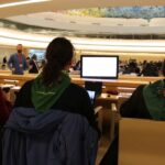 An image showing La Via Campesina's peasant leaders wearing the green LVC scarf and attending a UN session on Binding Treaty. The photo is shot from their back, so the faces cannot be seen.