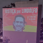 In the backdrop of citylights, a banner sits atop tall building calling for justice for Lindolfo. Inset, image of people paying homage to Lindolfo.